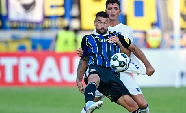 Saarbrücken's Kai Brünker, front, and Magdeburg's Tobias Müller in action during the DFB Cup first round soccer match between FC Saarbrücken and FC Magdeburg at Ludwigspark Stadium in Saarbrücken, Germany, Friday Aug. 15, 2025. (Uwe Anspach/dpa via AP)