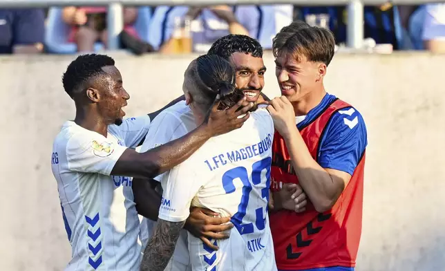 Magdeburg's Rayan Ghrieb, second right, celebrates scoring with teammates during the DFB Cup first round soccer match between FC Saarbrücken and FC Magdeburg at Ludwigspark Stadium in Saarbrücken, Germany, Friday Aug. 15, 2025. (Uwe Anspach/dpa via AP)