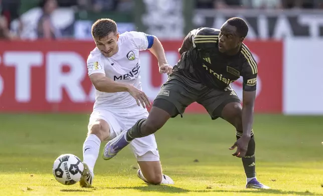 Gütersloh's Björn Rother, left, and Berlin's Ilyas Ansah in action during the DFB Cup first round between FC Gütersloh and 1. FC Union Berlin in Gütersloh, Germany, Friday Aug. 15, 2025. (David Inderlied/dpa via AP)