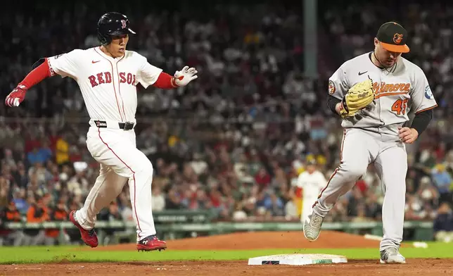 Boston Red Sox's Masataka Yoshida, left, grounds out as Baltimore Orioles pitcher Keegan Akin (45) makes the force in the sixth inning of a baseball game at Fenway Park, Tuesday, Aug. 19, 2025, in Boston. (AP Photo/Charles Krupa)