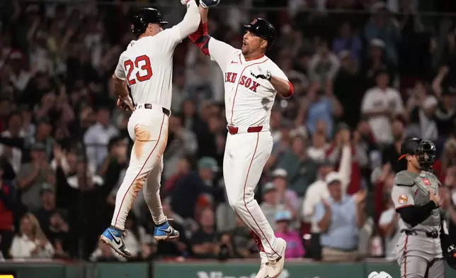Boston Red Sox designated hitter Nathaniel Lowe, right, is congratulated by Romy Gonzalez (23) after his game-tying, two-run home run in the bottom of the ninth inning of a baseball game against the Baltimore Orioles at Fenway Park, Tuesday, Aug. 19, 2025, in Boston. (AP Photo/Charles Krupa)