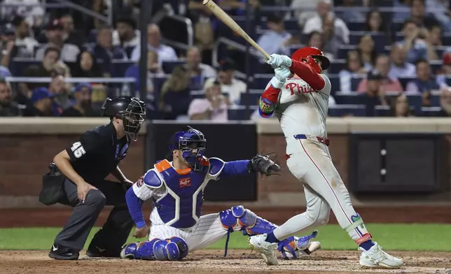 Philadelphia Phillies' Bryce Harper hits a single leading Weston Wilson and Trea Turner to score during the fifth inning of a baseball game against the New York Mets, Tuesday, Aug. 26, 2025, in New York. (AP Photo/Pamela Smith)