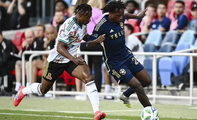 Vancouver Whitecaps midfielder Jean-Claude Ngando, right, controls the ball against San Jose Earthquakes defender DeJuan Jones, left, during the first half of an MLS soccer match Saturday, Aug. 9, 2025, in San Jose, Calif. (AP Photo/Thien-An Truong)