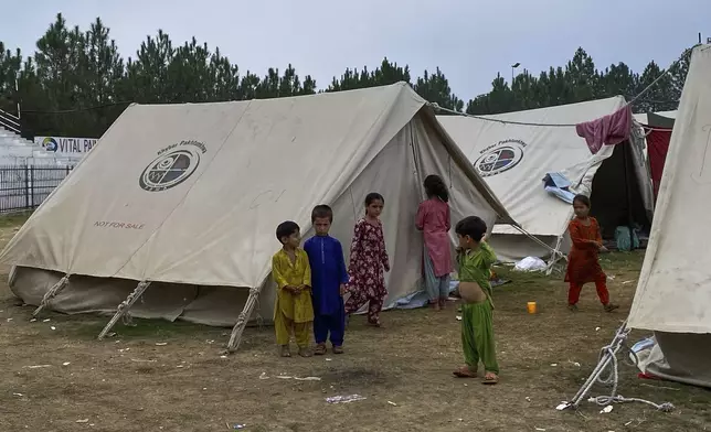 Children, who with their family members fled their homes after security forces launched a targeted operation against militants, stand at a camp set up in a sports complex at Khar, in the Bajaur district of Khyber Pakhtunkhwa province bordering Afghanistan, Thursday, Aug. 14, 2025. (AP Photo/Qyass Khan)