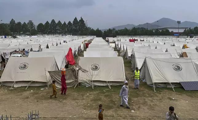Internally displaced people, who fled their homes after security forces launched a targeted operation against militants, walk at a camp set up in a sports complex at Khar, in the Bajaur district of Khyber Pakhtunkhwa province bordering Afghanistan, Thursday, Aug. 14, 2025. (AP Photo/Qyass Khan)