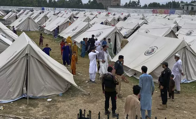 A police officer talks with internally displaced people, who fled their homes after security forces launched a targeted operation against militants, at a camp set up in a sports complex at Khar, in the Bajaur district of Khyber Pakhtunkhwa province bordering Afghanistan, Thursday, Aug. 14, 2025. (AP Photo/Qyass Khan)