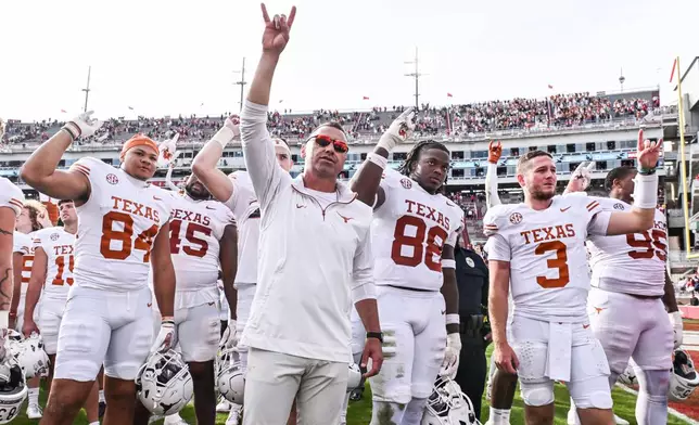 FILE - Texas tight end Jordan Washington (84), coach Steve Sarkisian, defensive back Barryn Sorrell (88) and quarterback Quinn Ewers (3) celebrate with their team after defeating Arkansas in an NCAA college football game Saturday, Nov. 16, 2024, in Fayetteville, Ark. (AP Photo/Michael Woods, File)