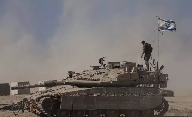 An Israeli soldier stands on the top of a tank parked on an area near the Israeli-Gaza border, as seen from southern Israel, Wednesday, Aug. 20, 2025. (AP Photo/Maya Levin)