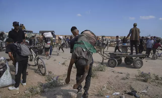 A Palestinian carries the body of a man killed while trying to receive aid near a distribution center operated by the U.S.-backed Gaza Humanitarian Foundation (GHF) in Netzarim, in the Gaza Strip, Monday, Aug. 4, 2025. (AP Photo/Abdel Kareem Hana)