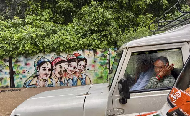 Stranded passengers sit in vehicles as a car is stuck in a landslide during heavy downpour blocking a national highway, near Rishikesh, India, Monday, Aug. 4, 2025. (AP Photo/Manish Swarup)