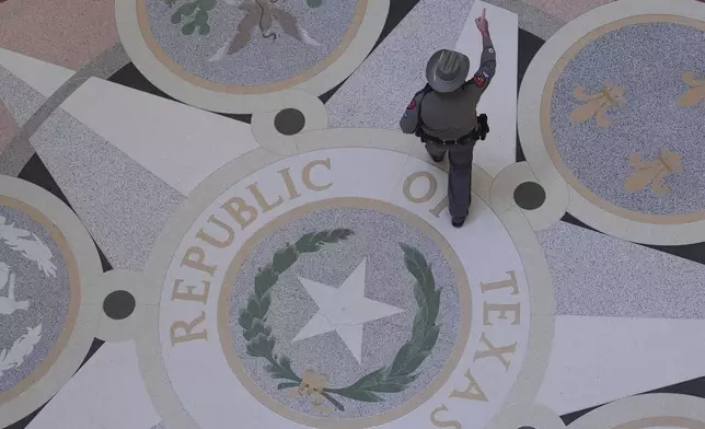 A Texas troopers passes the Texas Seal on the Rotunda of the Texas Capitol before debate on a bill for a redrawn U.S. congressional map during a special session in the Senate Chamber in Austin, Texas, Friday, Aug. 22, 2025. (AP Photo/Eric Gay)