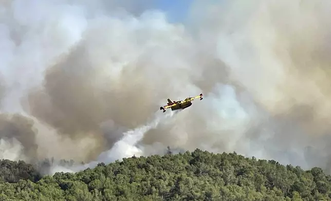 This photo provided by the Securite Civile shows a water bomber plane dropping water on the wildfire in the Corbieres massif , southern France, Tuesday, Aug. 5, 2025. (Securite Civile via AP)
