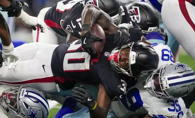 Atlanta Falcons running back Jashaun Corbin, center, is tackled by Dallas Cowboys safety Mike Smith Jr. (39) during the second half of a preseason NFL football game Friday, Aug. 22, 2025, in Arlington, Texas. (AP Photo/Tony Gutierrez)