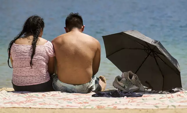 A couple cools off at Castaic Lake as temperatures rise on Wednesday, Aug. 20, 2025, in Castaic, Calif. (AP Photo/Damian Dovarganes)