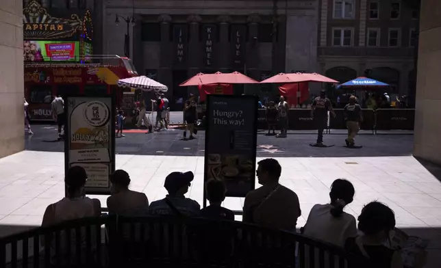 Tourists rest in the shade in the Hollywood section of Los Angeles, Tuesday, Aug. 19, 2025. (AP Photo/Jae C. Hong)