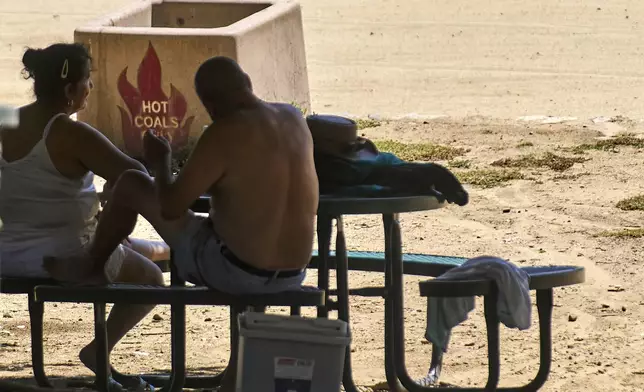 A couple sits in the shade as temperatures rise Wednesday, Aug. 20, 2025, at Castaic Lake in Los Angeles County, Calif. (AP Photo/Damian Dovarganes)