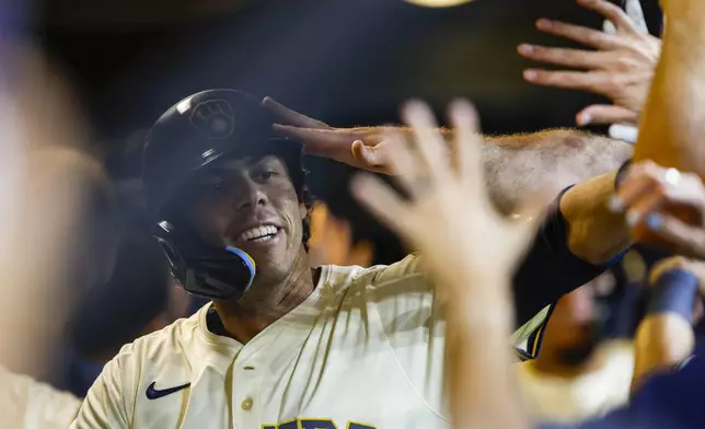 Milwaukee Brewers' Christian Yelich celebrates with teammates in the dugout after his two-run home run against the Pittsburgh Pirates during the fifth inning of a baseball game, Tuesday, Aug.12, 2025, in Milwaukee. (AP Photo/Jeffrey Phelps)