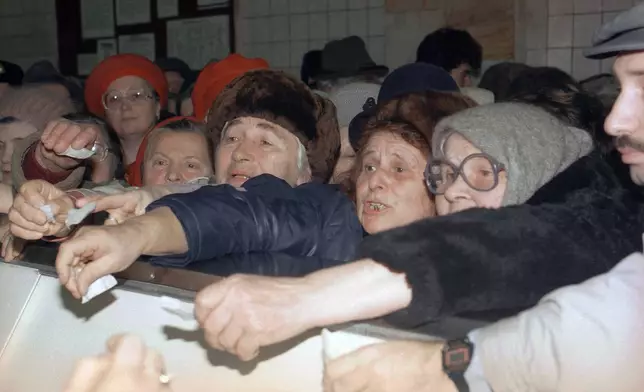 FILE - Ukrainian women shout while waving their coupons to buy butter at a state-owned shop in Kyiv, Dec. 3, 1991. (AP Photo/Liu Heung Shing, File)