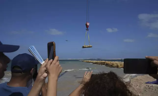 Reporters film an ancient artifact, unknown headless statue, as it is lifted out of the water in Abu Qir Bay at the Mediterranean city of Alexandria, Egypt, Thursday, Aug. 21, 2025. (AP Photo/Amr Nabil)