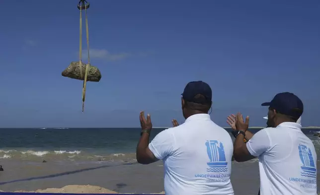 Antiquities workers celebrate as, unknown statue showing Sphinx, is lifted out of the water in Abu Qir Bay at the Mediterranean city of Alexandria, Egypt, Thursday, Aug. 21, 2025. (AP Photo/Amr Nabil)