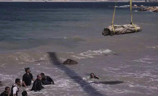 Divers watch one of the ancient artifacts, unknown priest, as it is lifted out of the water in Abu Qir Bay in the Mediterranean Sea city of Alexandria, Egypt, Thursday, Aug. 21, 2025. (AP Photo/Amr Nabil)