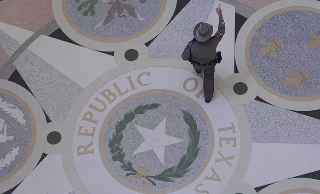 A Texas troopers passes the Texas Seal in the Rotunda of the Texas Capitol before debate on a bill on a redrawn U.S. congressional map during a special session in the Senate Chamber in Austin, Texas, Friday, Aug. 22, 2025. (AP Photo/Eric Gay)