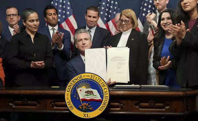 Gov. Gavin Newsom displays legislation he signed calling for a special election on a redrawn congressional map on Thursday, Aug. 21, 2025, in Sacramento, Calif. (AP Photo/Rich Pedroncelli)