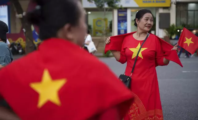 Women wear Vietnam's national flag as the nation celebrating Vietnam's 80th National Day in Hanoi, Friday, Aug. 29, 2025. (AP Photo/Vincent Thian)