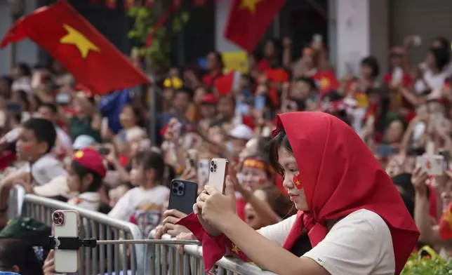 Vietnamese take picture with her mobile phone during military parade rehearsal for the Vietnam's 80th National Day celebration in old town of Hanoi, Vietnam, Saturday, Aug. 30, 2025. (AP Photo/Vincent Thian)