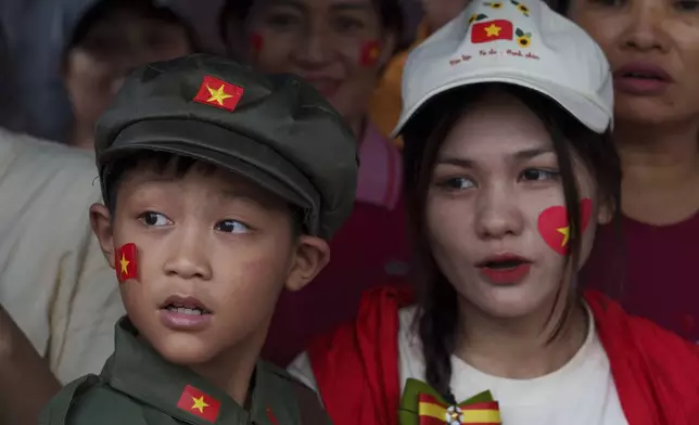 A child wears a traditional Vietnamese military uniform as people wait for a military parade rehearsal for the 80th National Day celebration in Hanoi, Vietnam, Saturday, Aug. 30, 2025. (AP Photo/Vincent Thian)