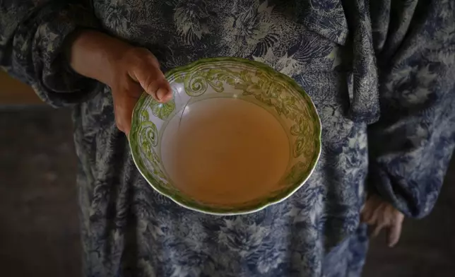 Palestinian woman Kifah Qadih, 34, poses with an empty plate to show she couldn't find food for her family amid shortages in the Gaza Strip, in Khan Yunis, Monday, July 28, 2025. (AP Photo/Abdel Kareem Hana)
