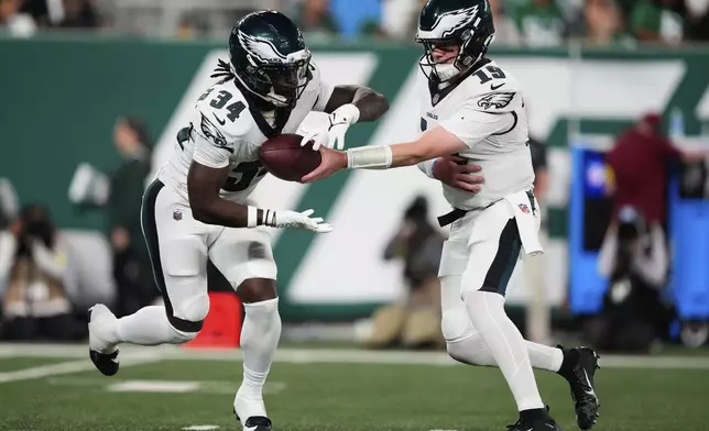 Philadelphia Eagles quarterback Kyle McCord (19) hands off to running back Montrell Johnson Jr. (34) in the first half of a preseason NFL football game in East Rutherford, N.J., Friday, Aug. 22, 2025. (AP Photo/Yuki Iwamura)