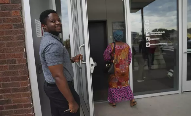 Mugisha Gloire, a Congolese refugee who came as a child to Iowa, holds the door open for driver's ed participants at St. Paul's United Methodist Church on Saturday, Aug. 9, 2025, in Cedar Rapids, Iowa. (AP Photo/Jessie Wardarski)