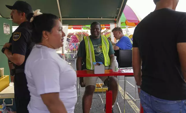 Roger Atchou, center, a father of two from Togo volunteers at the St. Jude Catholic Church's Sweet Corn Festival on Saturday, Aug. 9, 2025, in Cedar Rapids, Iowa. (AP Photo/Jessie Wardarski)