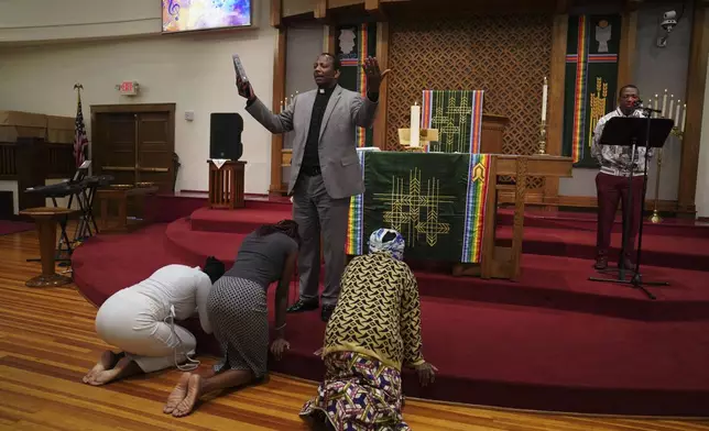 The Rev. Daniel Niyonzima, a refugee from Burundi who arrived in the United States with his wife 20 years ago, prays with congregants in Kirundi, one of Burundi's languages, during service at St. Paul's United Methodist Church on Sunday, Aug. 10, 2025, in Cedar Rapids, Iowa. (AP Photo/Jessie Wardarski)