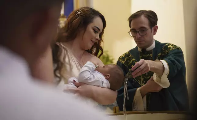 Gabriela Plasencia, originally from the Mexican state of Jalisco, holds her 4-month-old nephew Gael as he's baptized at Immaculate Conception Catholic Church on Sunday, Aug. 10, 2025, in Cedar Rapids, Iowa. (AP Photo/Jessie Wardarski)