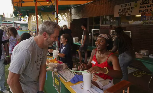 Chloe Mutombo, right, daughter of immigrant parents from Congo, volunteers at the St. Jude Catholic Church's Sweet Corn Festival, on Saturday, Aug. 9, 2025, in Cedar Rapids, Iowa. (AP Photo/Jessie Wardarski)