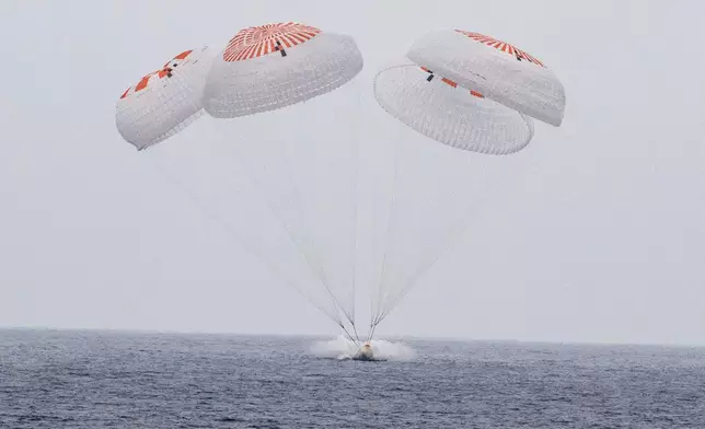 In this image provided by NASA, SpaceX capsule carrying four astronauts, parachutes into the Pacific Ocean off the Southern California coast on Saturday, Aug. 9, 2025. (Keegan Barber/NASA via AP)