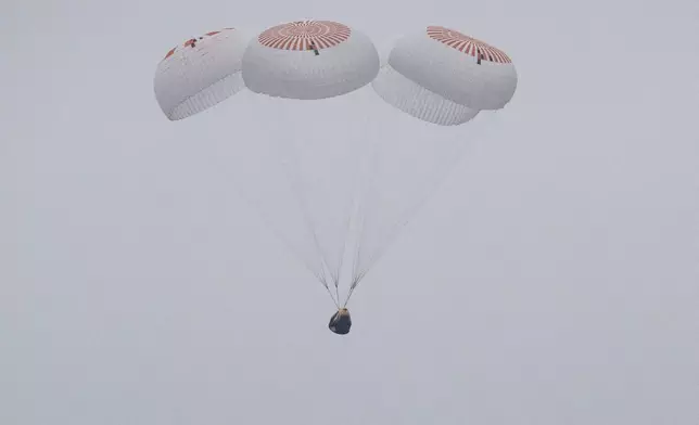 In this image provided by NASA, SpaceX capsule carrying four astronauts, parachutes into the Pacific Ocean off the Southern California coast on Saturday, Aug. 9, 2025. (Keegan Barber/NASA via AP)