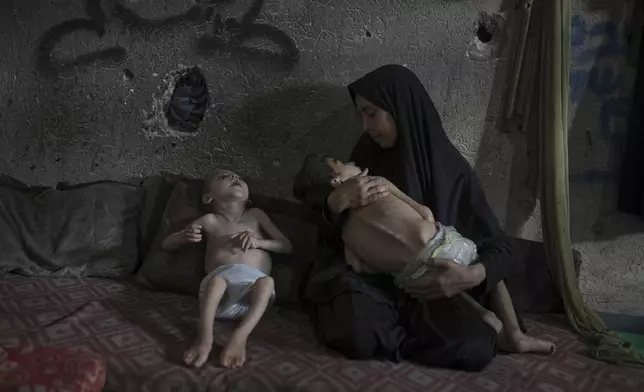 Samah Matar poses for a photo with her sons Yousef, 6, in her arms, and Amir, 4, who suffer from malnutrition and cerebral palsy, at a U.N.-run school in Gaza City, Saturday, July 26, 2025. In Gaza, malnutrition is often worsened by preexisting conditions and compounded by illnesses linked to inadequate health care and poor sanitation, largely the result of the ongoing war. (AP Photo/Jehad Alshrafi)