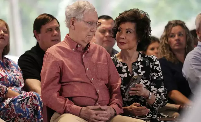 Sen. Mitch McConnell, R-Ky., looks at a phone held by his wife, Elaine Chao, at the annual Fancy Farm picnic Saturday, Aug. 2, 2025, in Fancy Farm, Ky. (AP Photo/Mark Humphrey)