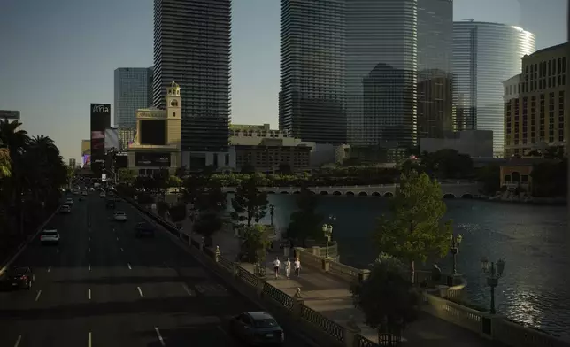 People walk along the Las Vegas Strip, Friday, Aug. 8, 2025, in Las Vegas. (AP Photo/John Locher)