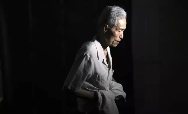FILE - Sumiteru Taniguchi, 86, a survivor of the 1945 atomic bombing of Nagasaki, puts his cloth on after posing for photographs during an interview at his office in Nagasaki, southern Japan, June 30, 2015. (AP Photo/Eugene Hoshiko)