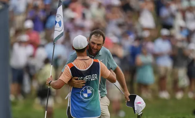 Scottie Scheffler, right, hugs his caddie Michael Cromie, left, on the 18th green after winning the BMW Championship golf tournament Sunday, Aug. 17, 2025, in Owings Mills, Md. (AP Photo/Stephanie Scarbrough)