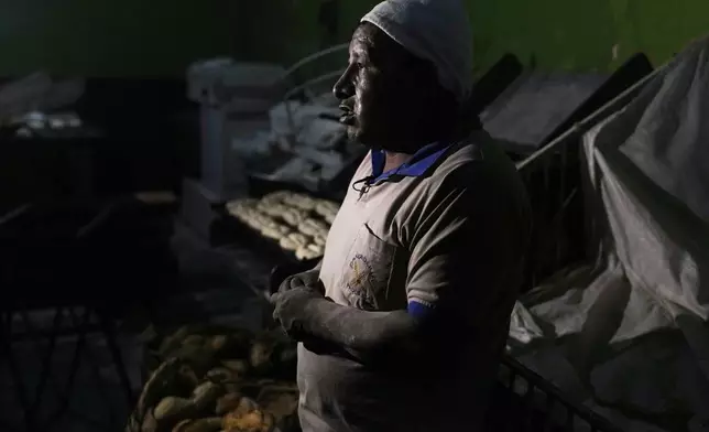 Baker Juan de Dios Castillo gives an interview while baking "pan de batalla," or battle bread, made with government subsidized flour, in El Alto, Bolivia, Friday, Aug. 8, 2025. (AP Photo/Juan Karita)