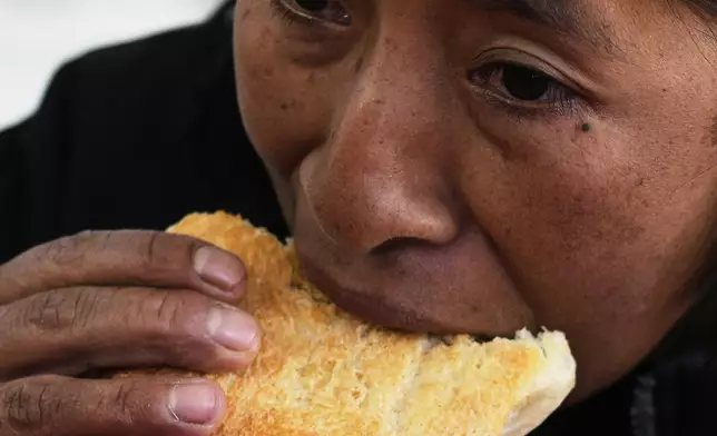 Rosario Manuel Uchura eats "pan de batalla," or battle bread, made with government subsidized flour, inside a restaurant at a market in La Paz, Bolivia, Saturday, Aug. 9, 2025. (AP Photo/Juan Karita)