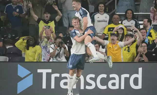 Nashville SC defender Josh Bauer, right, congratulates forward Sam Surridge, left, after scoring a goal during the first half of an MLS soccer match against Orlando City, Saturday, Aug. 23, 2025, in Nashville, Tenn. (AP Photo/George Walker IV)