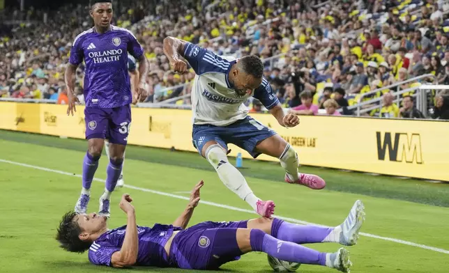 Orlando City defender Rodrigo Schlegel, slides underneath Nashville SC midfielder Hany Mukhtar, above as during the second half of an MLS soccer match Saturday, Aug. 23, 2025, in Nashville, Tenn. (AP Photo/George Walker IV)