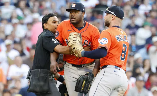 Home plate umpire Gerry Davis, left, and Houston Astros first baseman Christian Walker (8) restrain Astros pitcher Hector Neris, center, at the end of the seventh inning of a baseball game against the Boston Red Sox, Saturday, Aug. 2, 2025, in Boston. (AP Photo/Greg M. Cooper)