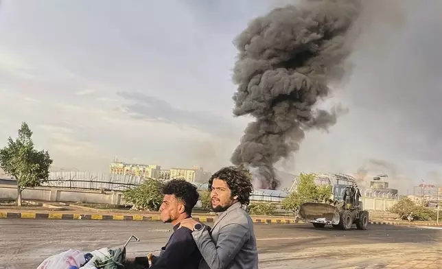 People ride a motorbike as smoke billows following Israeli airstrikes on multiple areas including a power planet and a gas station in Sanaa, Yemen, Sunday, Aug. 24, 2025. (AP Photo)